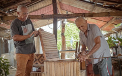 Antônio Luiz Ribeiro da Neves, conhecido como Tauru, ao lado do pai, José Fernandes Neves, o Seu Zeca, mestre artesão de Porto Nacional. A produção de móveis em madeira de buriti segue como ofício familiar, mantendo a prática ativa entre gerações 
