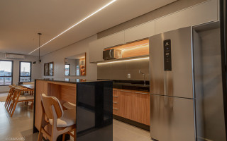 No modelo decorado, sala de estar, de jantar e cozinha estão integrados no mesmo ambiente, com o uso de móveis planejados para otimização dos espaços