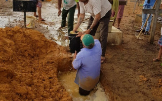 Com baldes, parentes retiram água de cova para fazer sepultamento