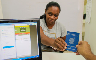 Atendimento no Sine Tocantins: trabalhadora apresenta carteira de trabalho durante orientação sobre serviços e oportunidades de emprego.