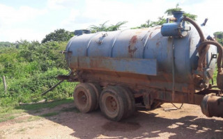 Caminhão limpa-fossa despejando detritos próximo a lavouro