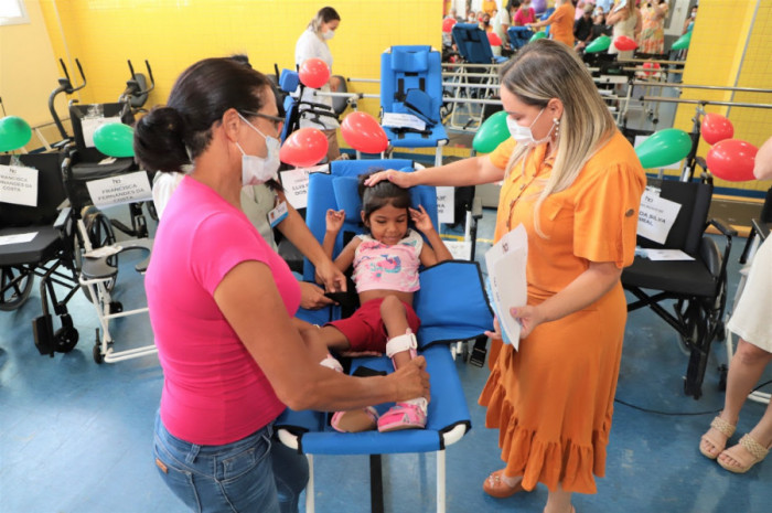 A cadeira de banho da Emily, de 7 anos, se parece com uma pequena maca, que pode ser elevada para que o cuidador faça a limpeza da menina com mais conforto e qualidade no chuveiro. 